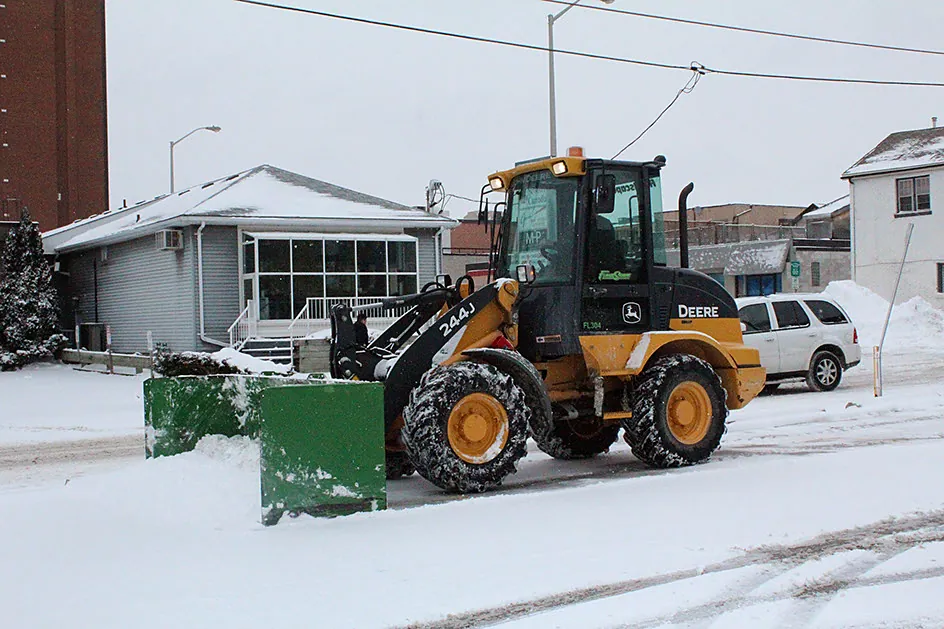 Loader with a snow pusher clearing a commercial lot