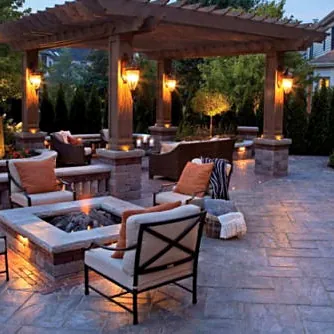 Pergola, fire pit and lit seat walls at dusk